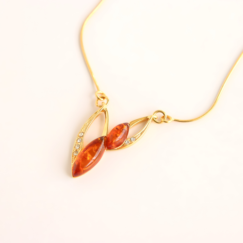 Gold amber necklace with amber-colored pendant on a white background
