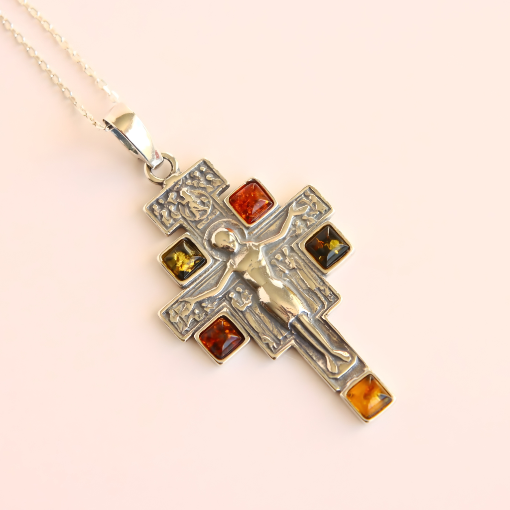 amber cross necklace with embedded amber stones on a light pink background