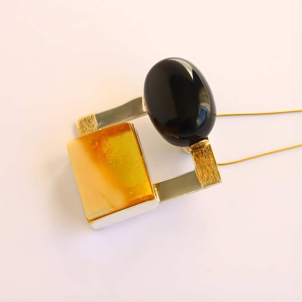 amber necklace with a black stone and gold accents on a white background