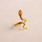 Gold snake ring with a amber stone on a beige background