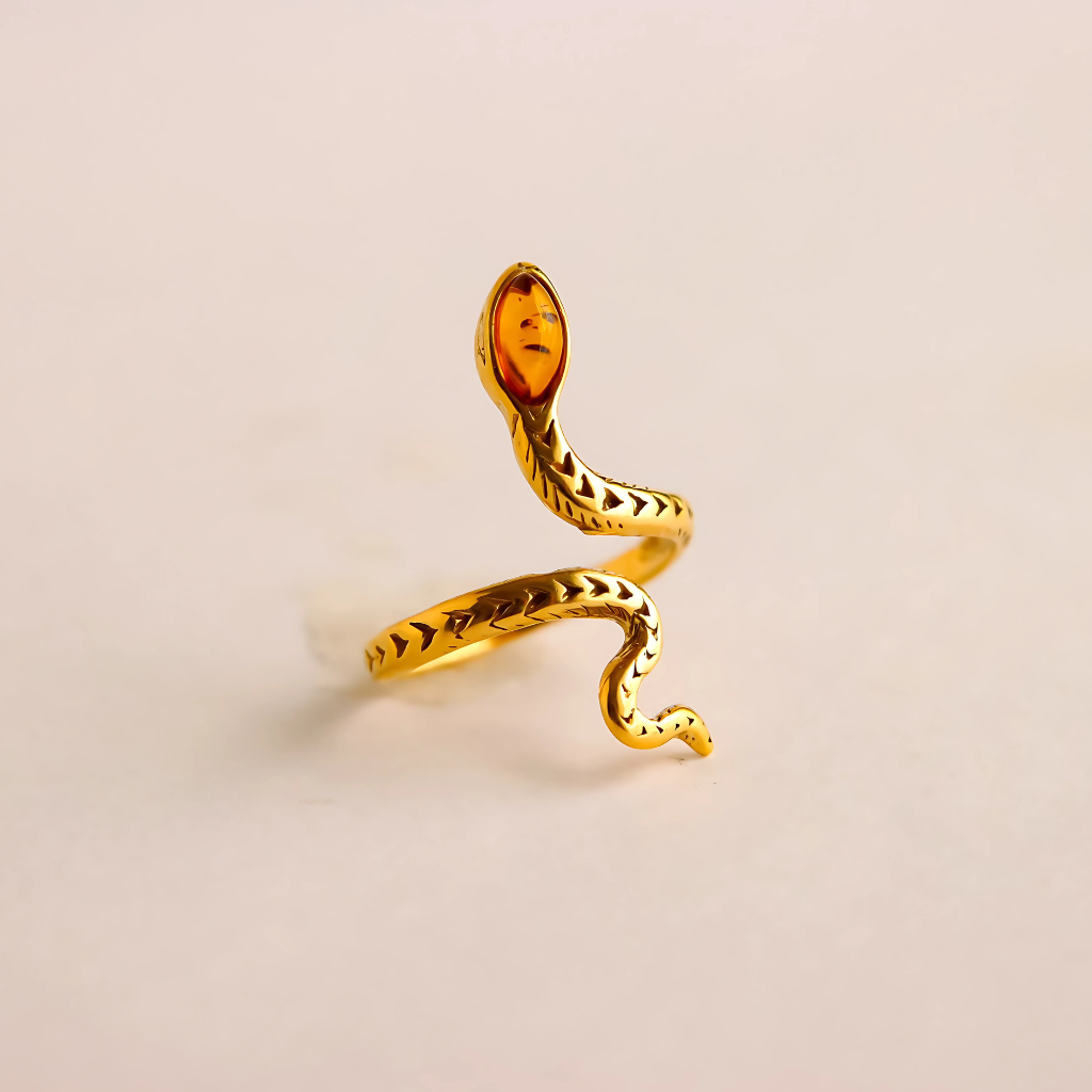 Gold snake ring with a amber stone on a beige background