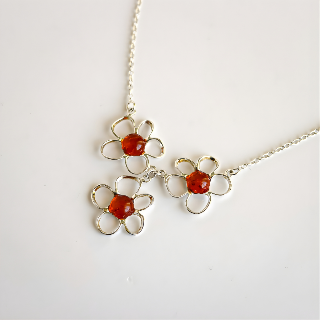 amber flower necklace with red gemstones on a white background