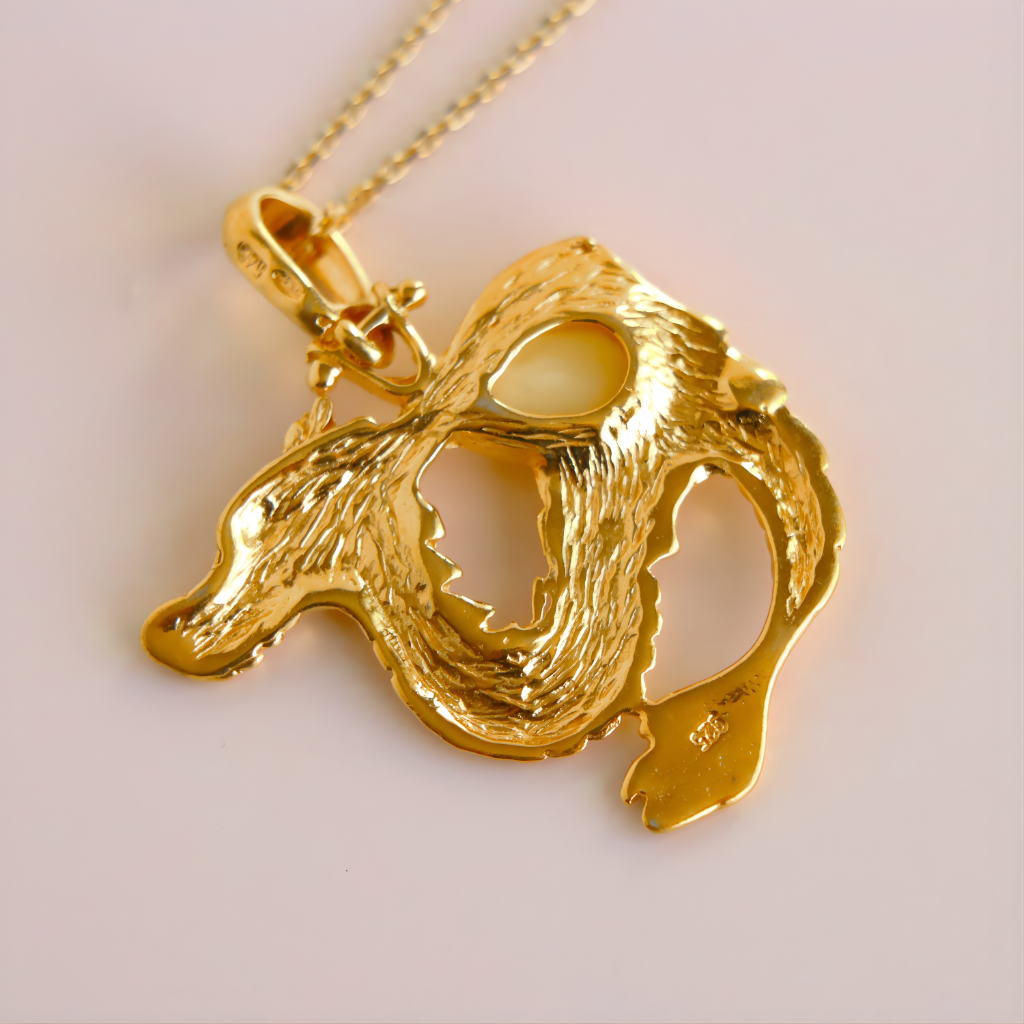 Gold dragon pendant on a chain against a light background