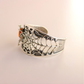 Silver amber bracelet with spider web design on a beige background
