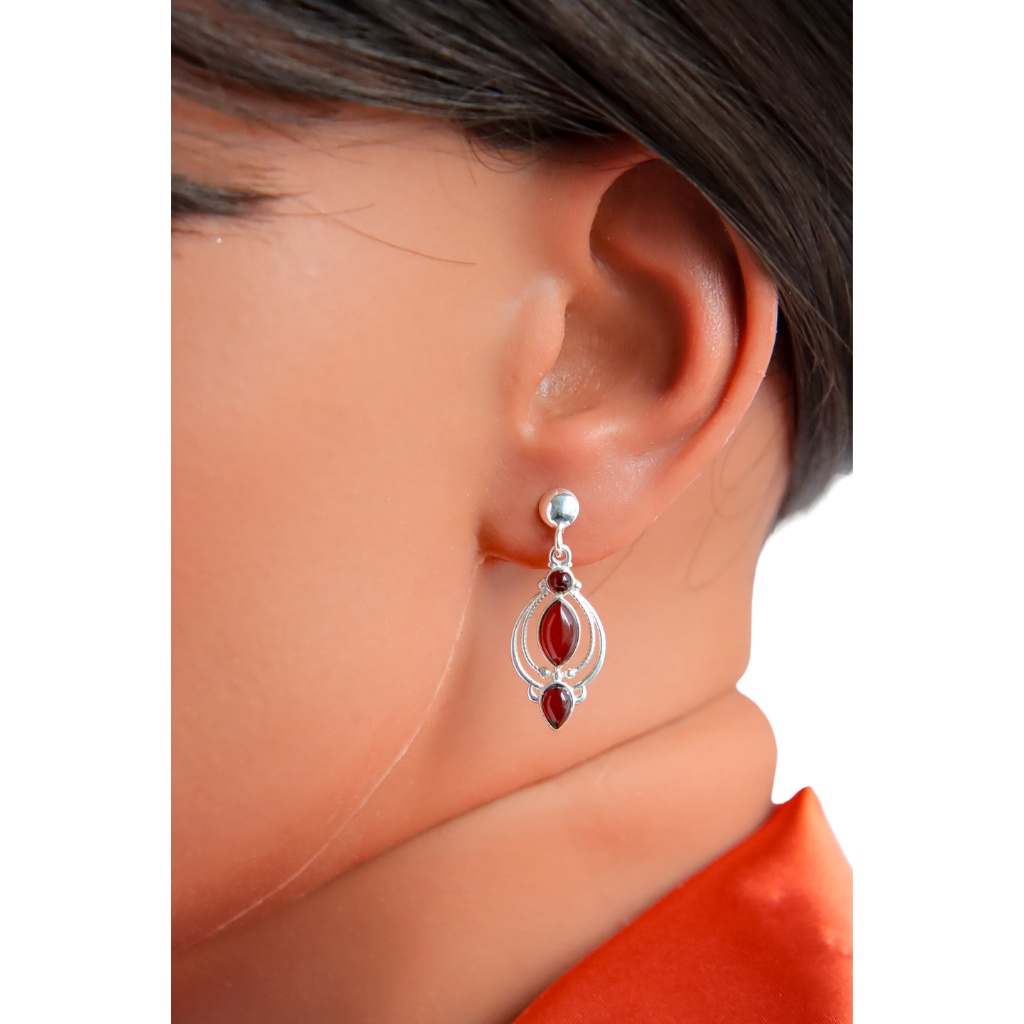 Victorian style Baltic cherry amber dangle earrings in sterling silver displayed on an ear.