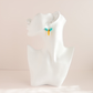 A pair of small turquoise hoop earrings with turquoise blue and orange dangling beads, displayed on a white mannequin head against a soft beige background.