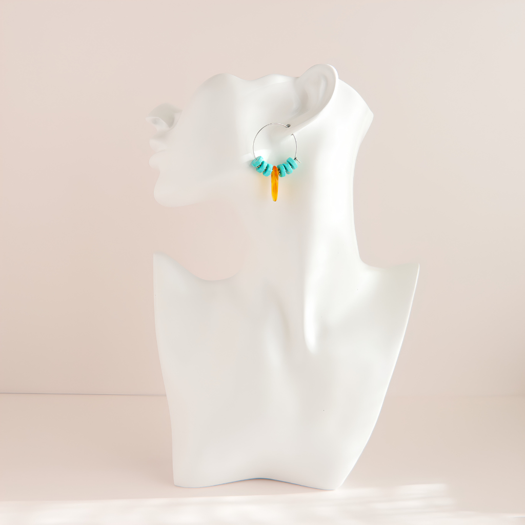 A pair of small turquoise hoop earrings with turquoise blue and orange dangling beads, displayed on a white mannequin head against a soft beige background.