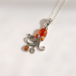 A silver amber pendant necklace featuring a stylized octopus design set with amber-colored stones, including a large round amber cabachon and two smaller accent stones, on a silver chain against a plain white background.