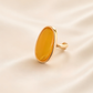 Gold amber ring with amber-colored stone on a beige background