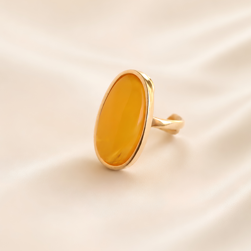 Gold amber ring with amber-colored stone on a beige background