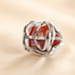 Silver flower ring with a red stone on a beige background