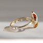 A sterling silver amber ring with a marquise-cut amber gemstone, shown in a close-up side profile on a light gray background with a soft shadow.