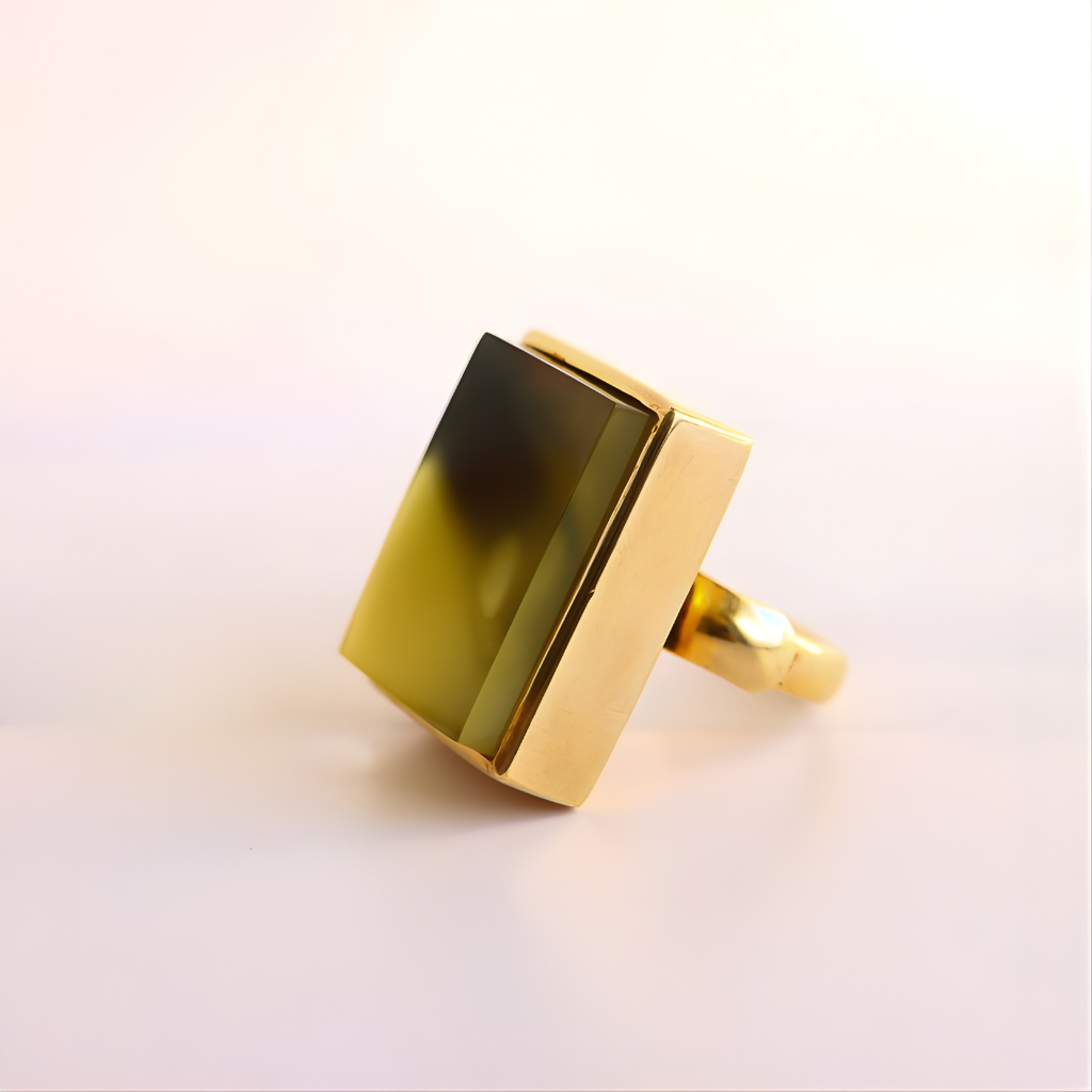 Gold amber ring with a rectangular green stone on a light background