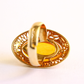 Gold amber ring with a decorative band on a white background