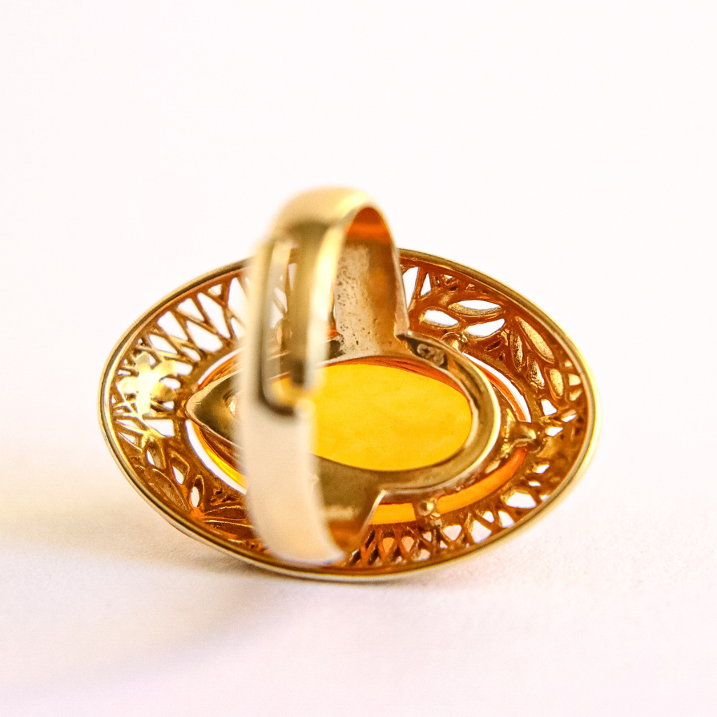Gold amber ring with a decorative band on a white background