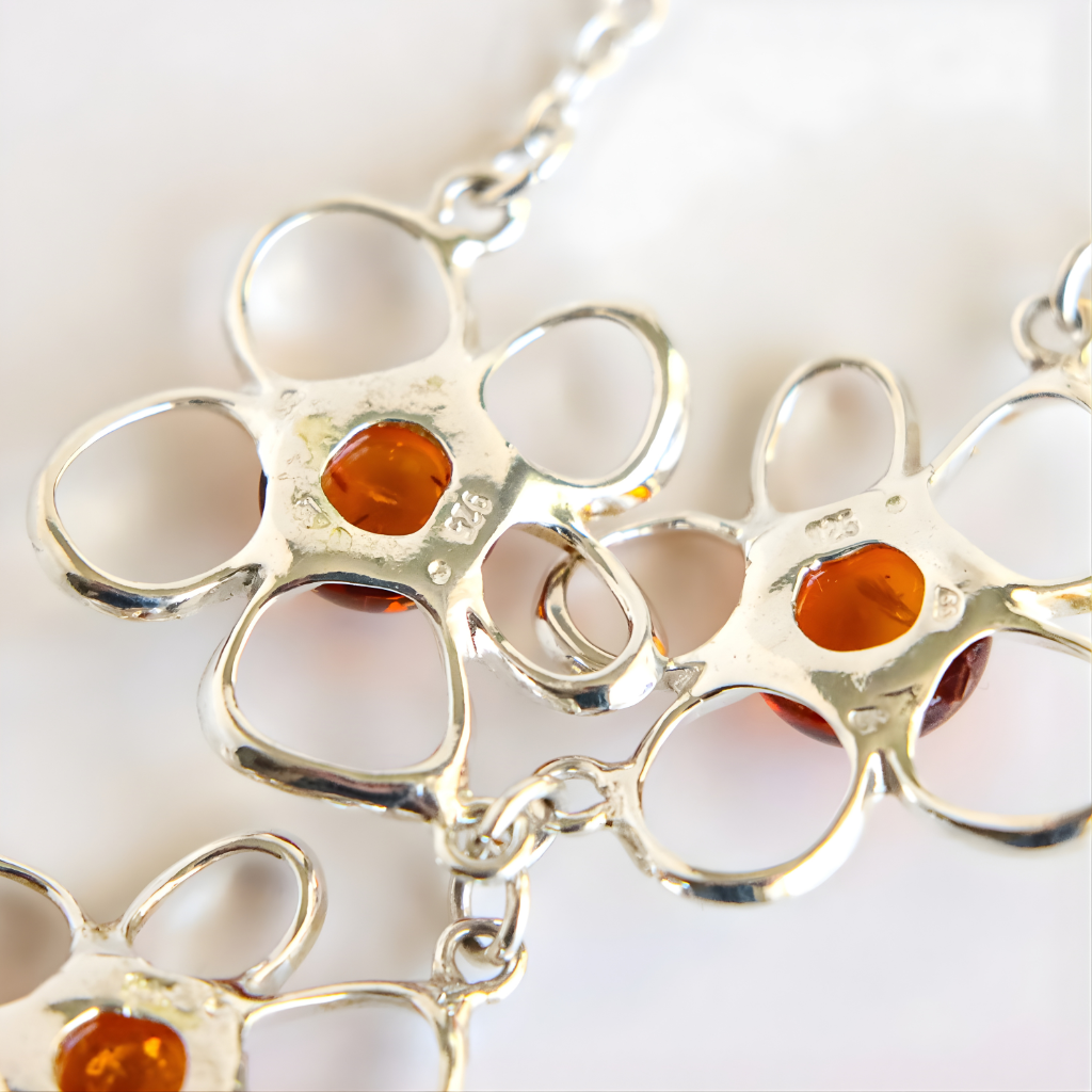 Silver amber flower necklace with circular links and amber-colored stones on a white background