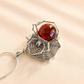 Silver spider web amber necklace with a red gemstone on a beige background