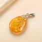 Teardrop-shaped amber pendant on a beige background