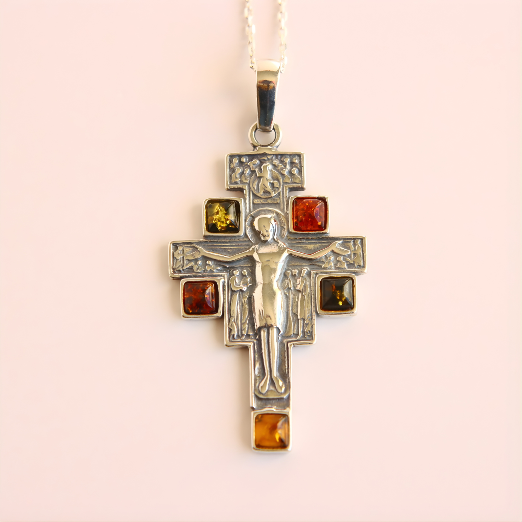 amber cross necklace with embedded amber stones on a light pink background