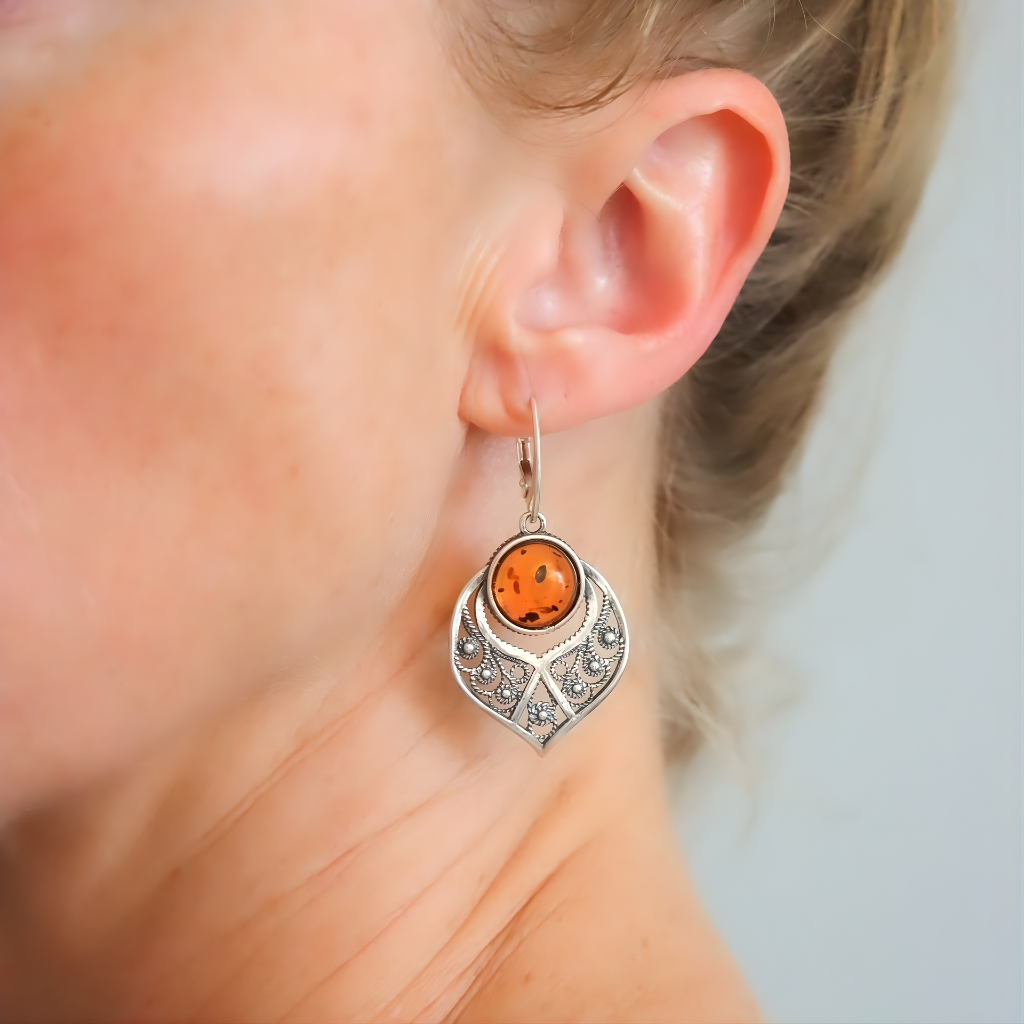 sterling Silver earrings with an orange gemstone worn by a person