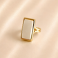 White amber ring with rectangular cream amber stone and polished gold-tone split band.