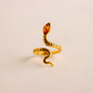 Gold snake ring with a amber stone on a beige background