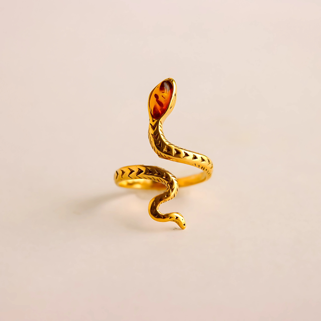Gold snake ring with a amber stone on a beige background