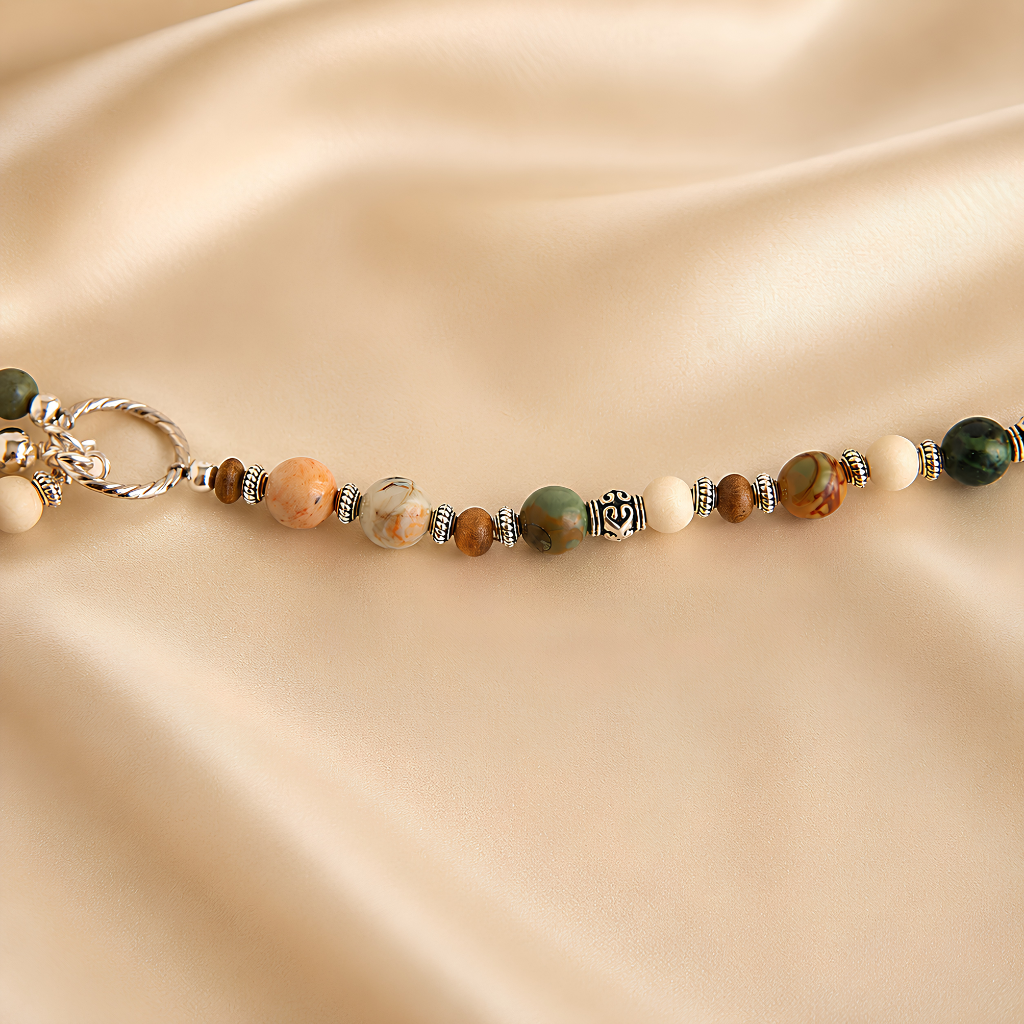 Beaded raven skull necklace with natural stones on a beige satin background