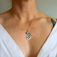 Person wearing a silver necklace with a multicolored amber pendant