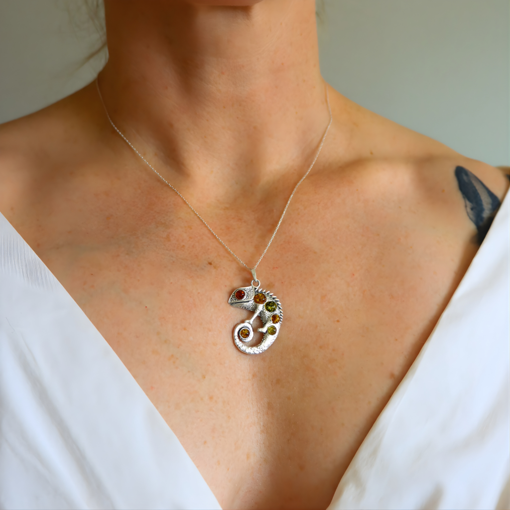 Person wearing a silver necklace with a multicolored amber pendant