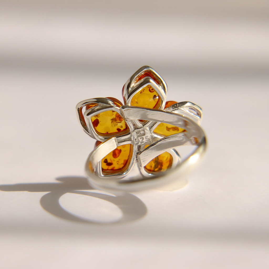 A silver amber flower ring featuring five amber-colored petal-shaped inlays with visible natural inclusions, set on a white background with a soft shadow.