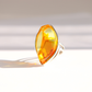 A silver amber statement ring featuring a large, faceted marquise-cut amber gemstone, photographed on a clean white surface with soft shadows.