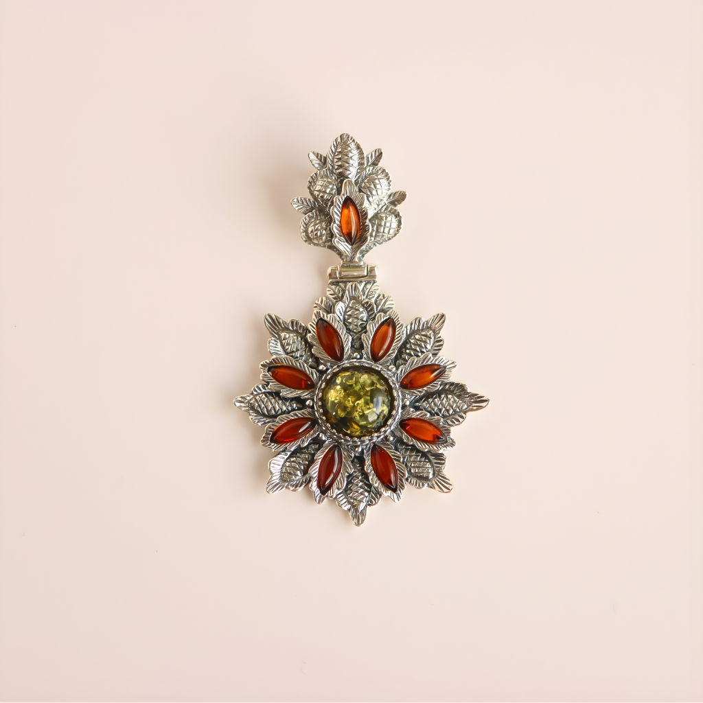 Decorative green amber floral pendant with starburst design and colored stones on a beige background
