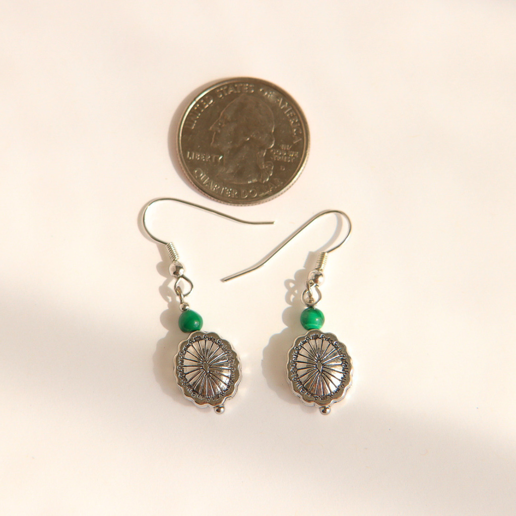 A pair of silver-toned western malachite dangle earrings with green beads and oval filigree charms, shown next to a US quarter coin for scale on a plain light background.