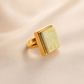 Gold amber ring with a square stone on a beige background