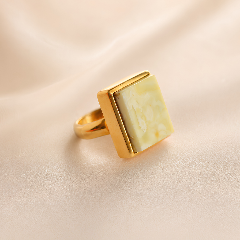 Gold amber ring with a square stone on a beige background