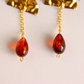 Teardrop-shaped vintage Lucite amber  drop earrings with gold-tone chains displayed against a light off-white background.