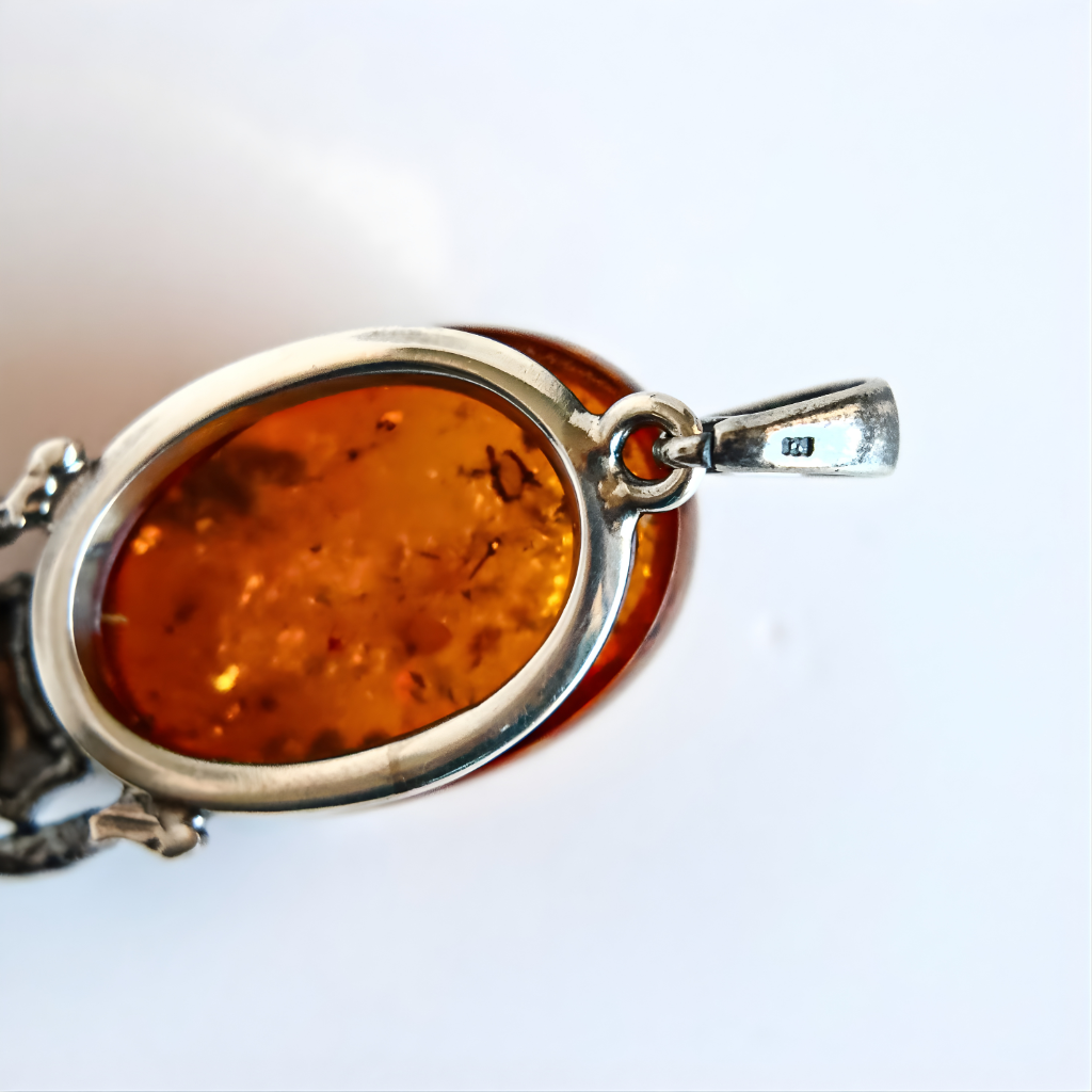 Amber pendant with silver frame on a white background