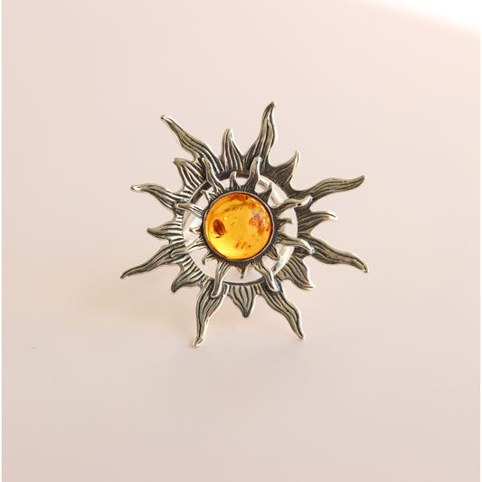 Silver sun ring  with a central amber gemstone on a beige background