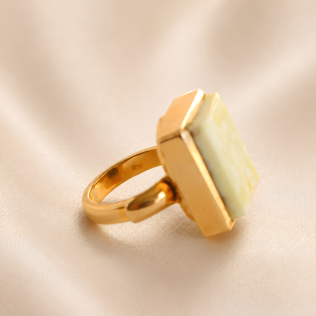 Gold amber ring with a rectangular stone on a beige background