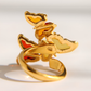 A gold-plated amber butterfly ring with colorful enamel wings in yellow, orange, and light green, set against a bright white background.