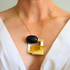 amber Necklace with a black and gold pendant on a person wearing a white top.