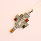 amber cross necklace with embedded amber stones on a light pink background