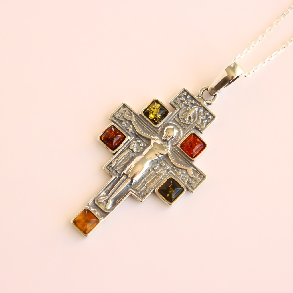 amber cross necklace with embedded amber stones on a light pink background