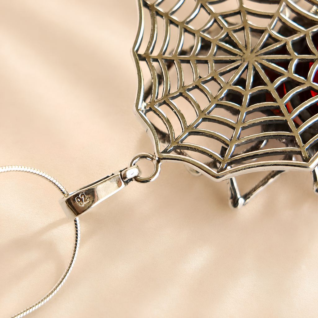 Silver spider web amber necklace on a beige background