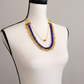 Angled view of a lapis, citrine, and olive jade statement necklace with gold plated brass chain.