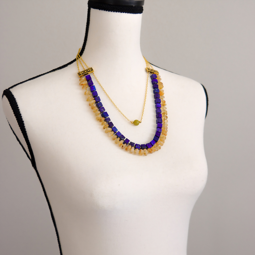 Angled view of a lapis, citrine, and olive jade statement necklace with gold plated brass chain.