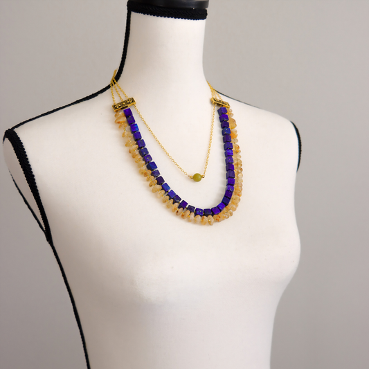 Angled view of a lapis, citrine, and olive jade statement necklace with gold plated brass chain.