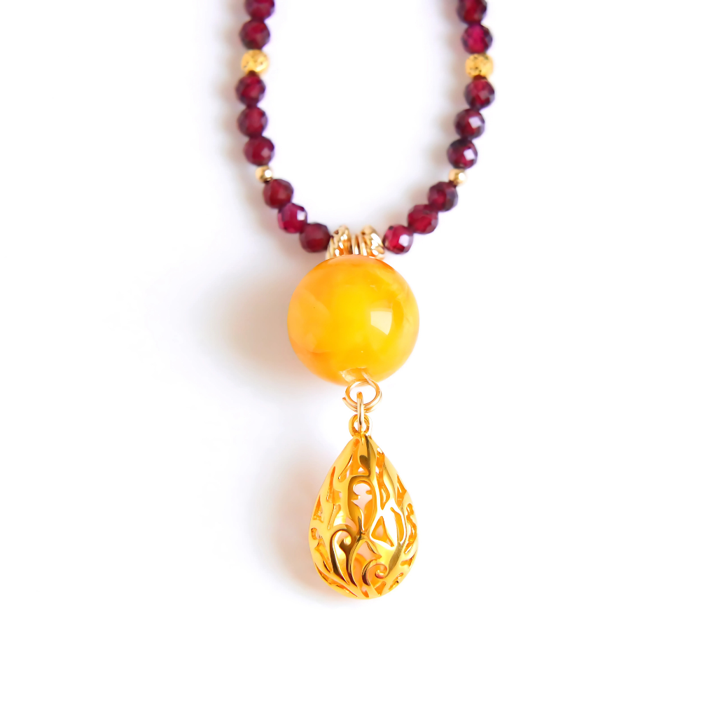 Detailed view of 14k gold-filled butterscotch amber necklace with pendant and garnet strand