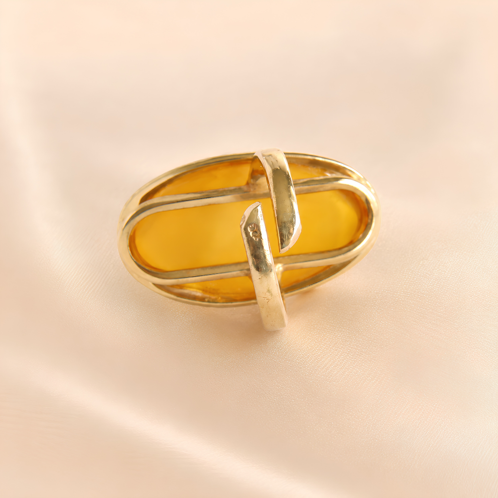 Gold amber ring with amber stone on a beige background